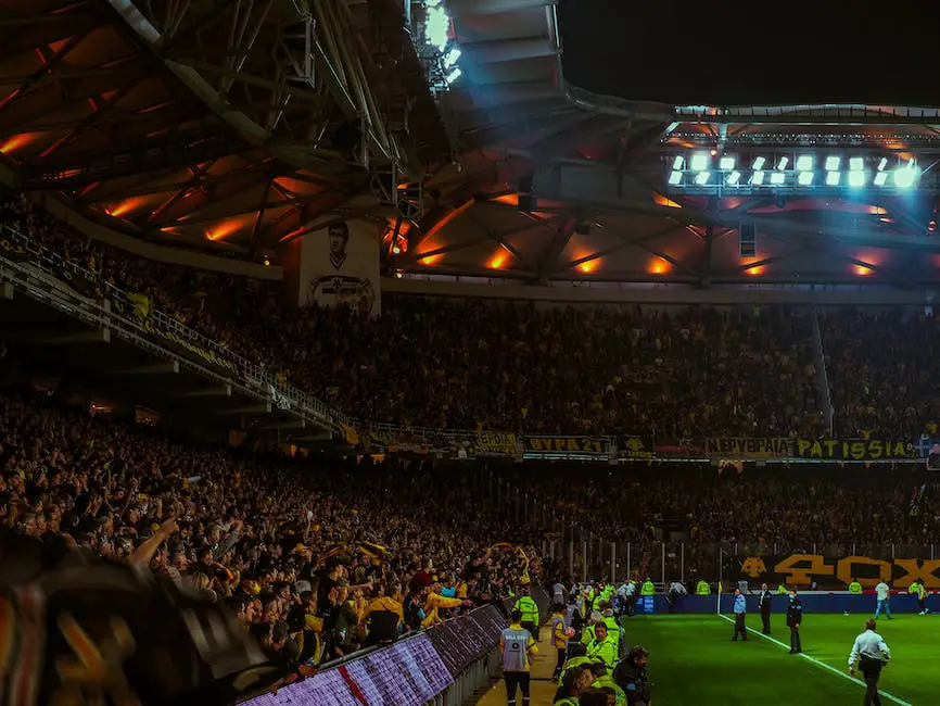 A group of football fans in a stadium, cheering on their team while wearing their team's colors and holding up signs and flags.