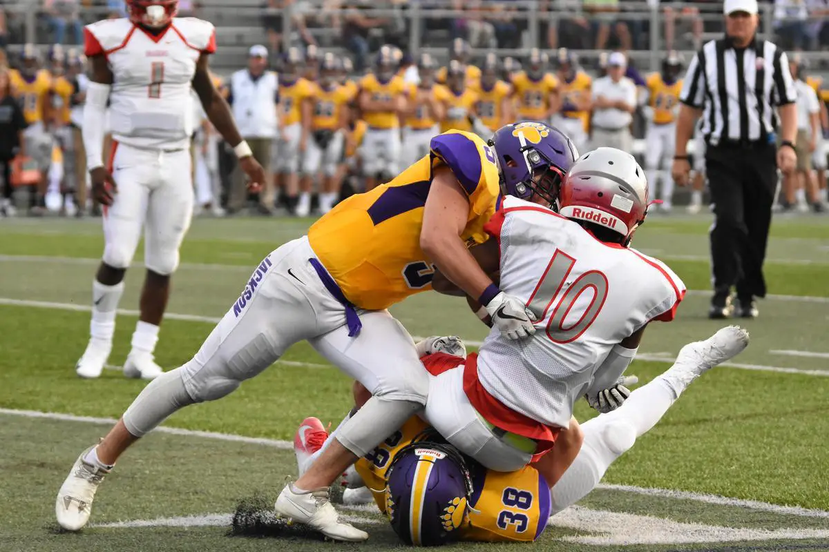 Two linebackers tackling a running back on the football field
